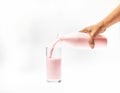 Pour strawberry milk from bottle into glass