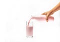 Pour strawberry milk from bottle into glass