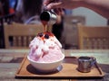 Pour strawberry sauce over a pink milk kakigori or Japanese shaved ice dessert flavored.