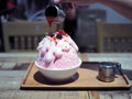 Pour strawberry sauce over a pink milk kakigori or Japanese shaved ice dessert flavored, topped with pink whipped cream.