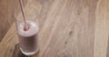 Pour strawberry yogurt into glass on wood table