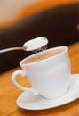 Pour sugar to milk coffee of classical white cup Royalty Free Stock Photo