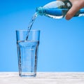 Pour water from plastic bottle into large glass. Bottle in hand of man. The sky with clouds. Royalty Free Stock Photo