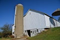 A poured silo stands tall behind a majestic old white barn Royalty Free Stock Photo