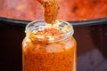 Pouring ajvar into the jar with spoon Royalty Free Stock Photo