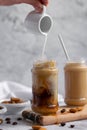 Pouring almond milk over iced coffee, refreshing energizing drink
