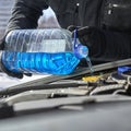 Pouring an antifreeze liquid in a windshield washer tank of a car close up Royalty Free Stock Photo