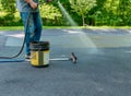 Pouring asphalt sealant on driveway