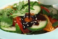 Pouring balsamic vinegar onto fresh vegetable salad in dish