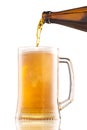 Pouring beer from bottle into a mug with foam isolated on white background. Royalty Free Stock Photo