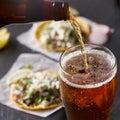 Pouring beer in front of mexican tacos