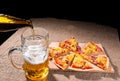 Pouring Beer into Glass next to Pizza Slices Royalty Free Stock Photo