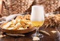 Pouring beer into the glass. Wheat spikelets with one mugs of beer on wooden background