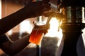 Pouring beer into a plastic glass. Sunset Royalty Free Stock Photo