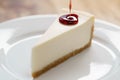 Pouring berry jam on slice of traditional new york cheesecake on white plate on wood table