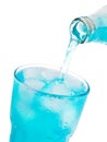 Pouring blue soda into glass with ice from bottle