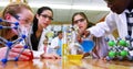 Pouring blue solution from beaker into flask in chemistry lab with lab coats and goggles Royalty Free Stock Photo