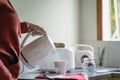 Pouring boiling water on a cup of tea with electric kettle in the morning. Unrecognizable person Royalty Free Stock Photo