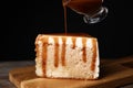 Pouring caramel sauce on slice of cake at table