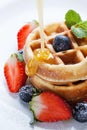 Pouring caramel sauce on waffles with strawberry and blueberry