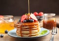 Pouring caramel syrup onto fresh pancakes with berries