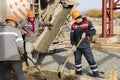 Pouring cement or concrete with a concrete mixer truck, construction site with a reinforced grillage foundation. Workers settle