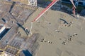 Pouring cement on the floors of residential multi-story building under construction using a concrete pump truck with high boom to Royalty Free Stock Photo