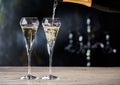 Pouring champagne into glasses. Black and gold background. Copy space for text.