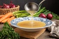 Pouring chicken bone broth from a ladle into a vintage plate