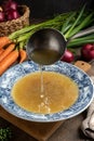 Pouring chicken bone broth into a vintage plate