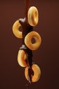 Pouring chocolate on doughnuts on brown background. 3d render