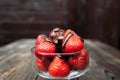 Pouring chocolate over strawberry, dark background