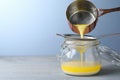 Pouring clarified butter into jar on grey table. Space for text Royalty Free Stock Photo