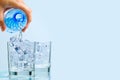 Pouring clean drinking water from blue plastic bottle into glass on blue background Royalty Free Stock Photo