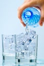 Pouring clean drinking water from blue plastic bottle into glass on blue background Royalty Free Stock Photo