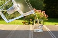 Pouring clear filtered water from a water filtration jug into a glass in green summer garden in a sunny summer day Royalty Free Stock Photo