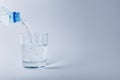 Pouring clear mineral water from plastic bottle into glass