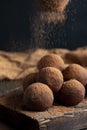 Pouring cocoa powder on enegry balls. Homemade Healthy vegan Raw Energy truffle Balls with on wooden cutting board.
