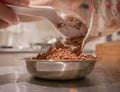 Pouring cocoa powder into a small stainless steel plate.