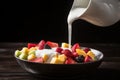 pouring coconut milk into a bowl of exotic tropical fruit salad Royalty Free Stock Photo