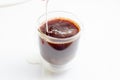 Pouring coffe with splash milk in a transparent cup on white background