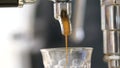 Pouring coffee stream from machine in cup