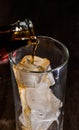 Pouring the cola from the bottle into a clear glass with ice Royalty Free Stock Photo