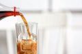 Pouring cola from bottle into glass on blurred background, closeup. Royalty Free Stock Photo