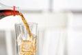 Pouring cola from bottle into glass on blurred background, closeup Royalty Free Stock Photo