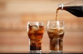 Pouring cola from bottle into glass with ice cubes on table Royalty Free Stock Photo