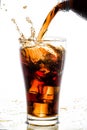 Pouring cola into glass with ice cubes