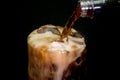 Pouring cola from plastic bottle into rocks glass with ice cubes Royalty Free Stock Photo