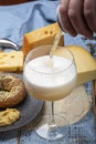 Pouring of cold belgian beer in glass, served in cafe with variety of hard cheeses, tasty european food Royalty Free Stock Photo