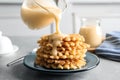 Pouring condensed milk from jug onto waffles on grey. Dairy product Royalty Free Stock Photo